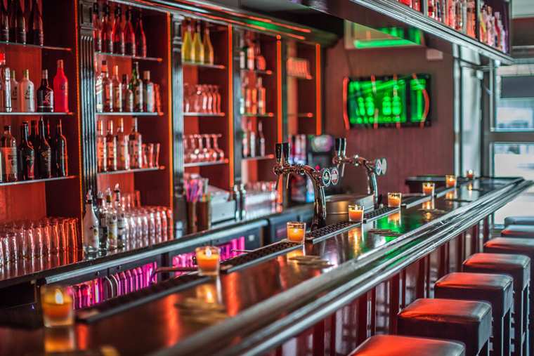 Bar met verlichte flessenwand en barkrukken